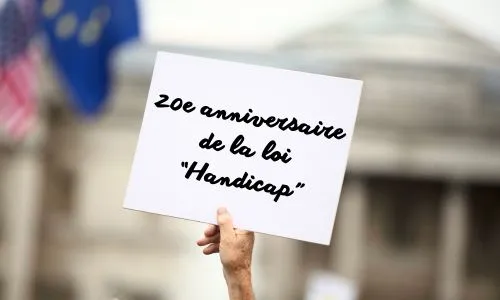 Manifestant avec une pancarte « 20e anniversaire de la loi ‘Handicap’ ».