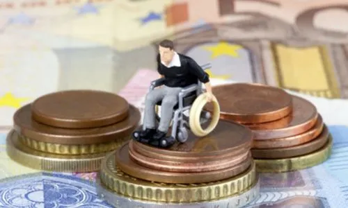 Une figurine d’un homme en fauteuil roulant installée sur des pièces et billets.