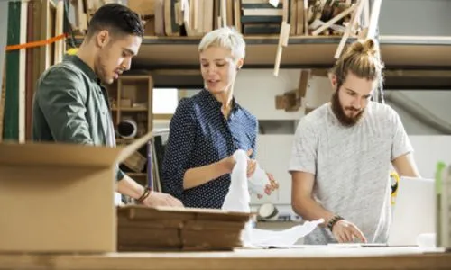 2 jeunes et une femme travaillent dans une entreprise qui fabrique des meubles.