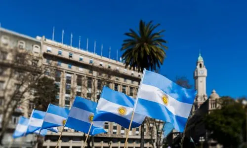 Plusieurs drapeaux de l’Argentine devant un bâtiment en ville.