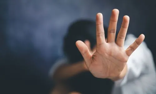 Une jeune femme prostrée fait « stop » avec sa main.