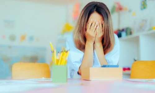 Une enseignante met les mains sur ses yeux, en signe de fatigue.