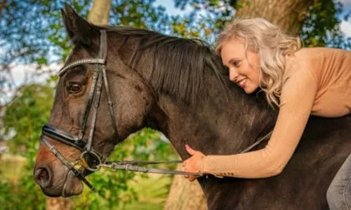 Jeune femme penchée sur l’encolure de son cheval.