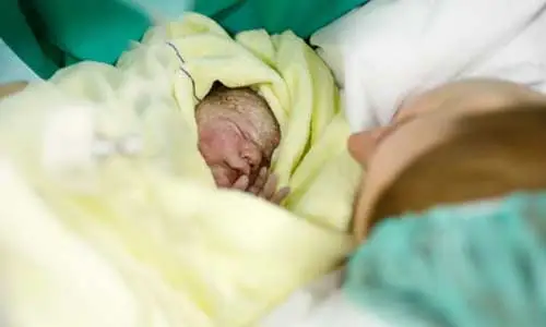 Une mère qui vient d’accoucher tient son bébé dans les bras.