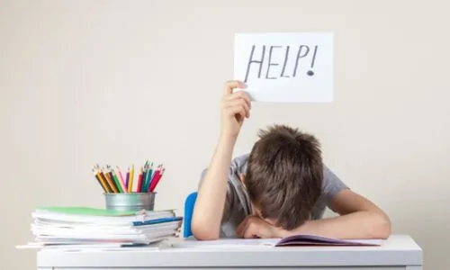 Un enfant pose sa tête sur son bras et brandit une pancarte « Help ! ».