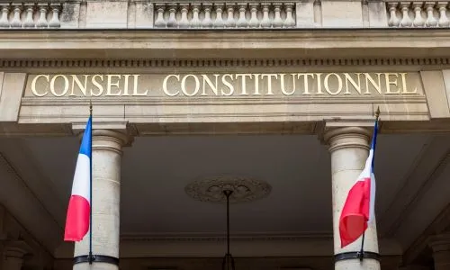 Façade du Conseil constitutionnel avec deux drapeaux français.