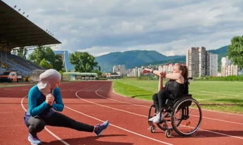 2 femmes, dont une en fauteuil roulant, s’échauffent sur une piste d’athlétisme.