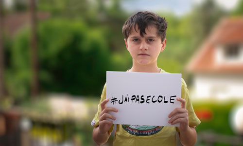 Un élève tient une feuille blanche avec l’inscription #Jaipasecole.