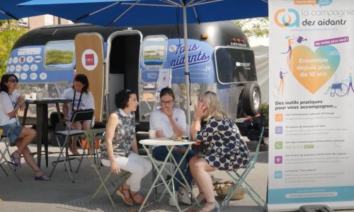 Plusieurs femmes discutent devant la Caravane des aidants.