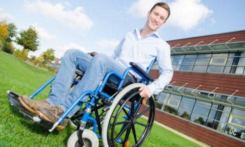 Un étudiant en fauteuil roulant devant une fac.