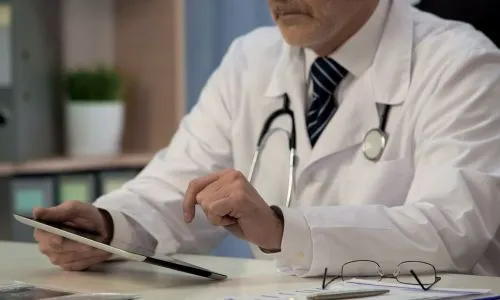 Un médecin regarde sa tablette numérique.