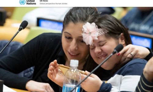 Jeune fille avec trisomie riant avec une autre femme dans l'hémicycle de l'ONU