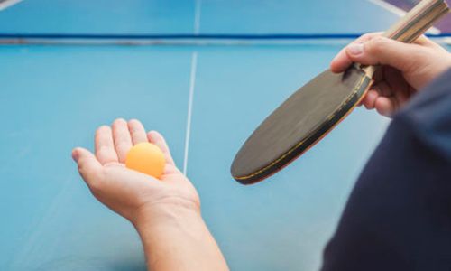 Les mains d’un joueur de tennis de table qui s’apprête à lancer sa balle.