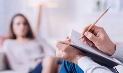 Un psychiatre prend des notes pendant une séance avec une patiente.