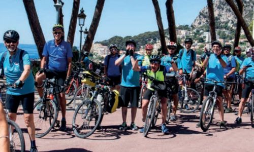 Des dizaines de psycyclistes à l’arrêt sur une route surplombant la mer.