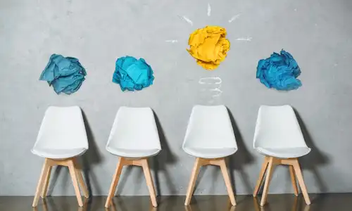 Chaises surmontées de papiers bleus sauf une avec un papier jaune