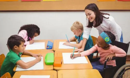 4 élèves en classe à côté de leur enseignante.