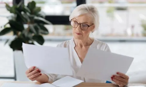 Une femme avec les cheveux blancs lit des documents.