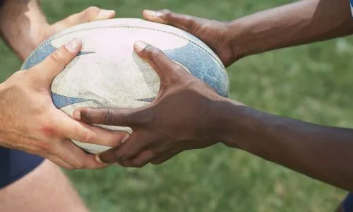 2 joueurs de rugby tiennent un ballon dans leurs mains.