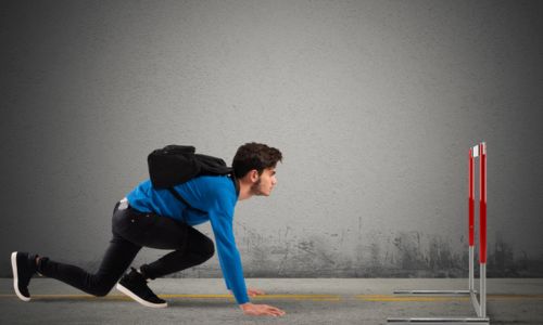 Un homme dans les starting-blocks, les yeux rivés sur une haie.